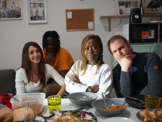 quattro persone di diverse etnie sedute a tavola prima di pranzo