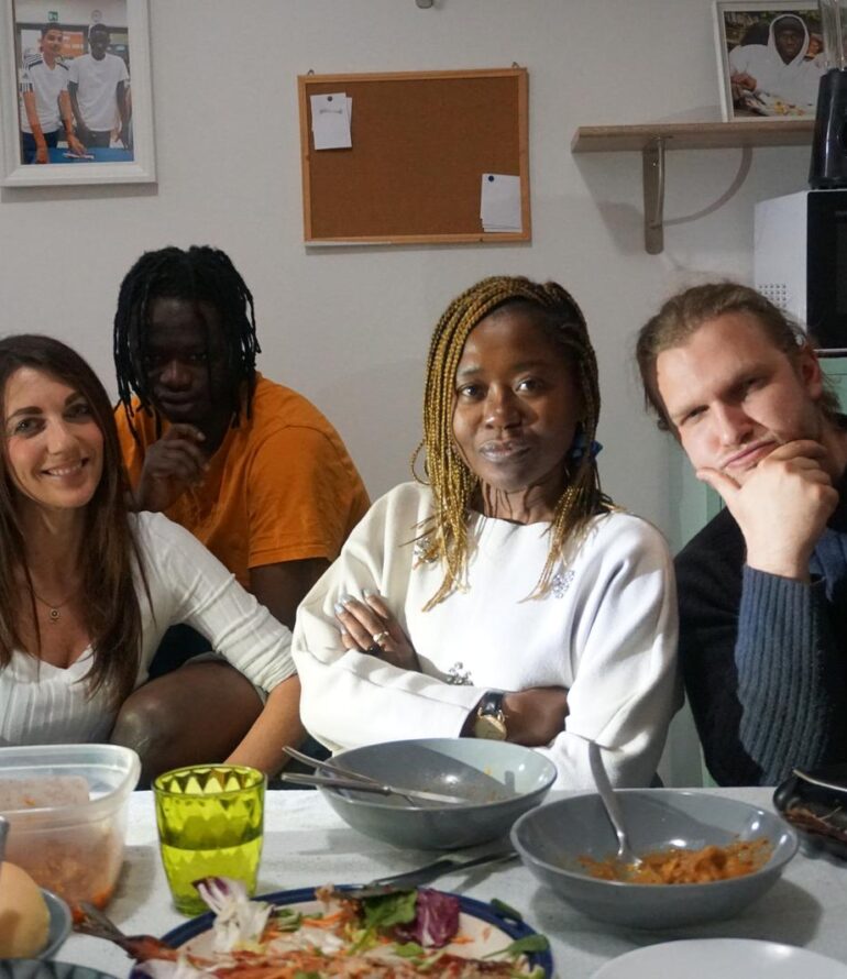 quattro persone di diverse etnie sedute a tavola prima di pranzo