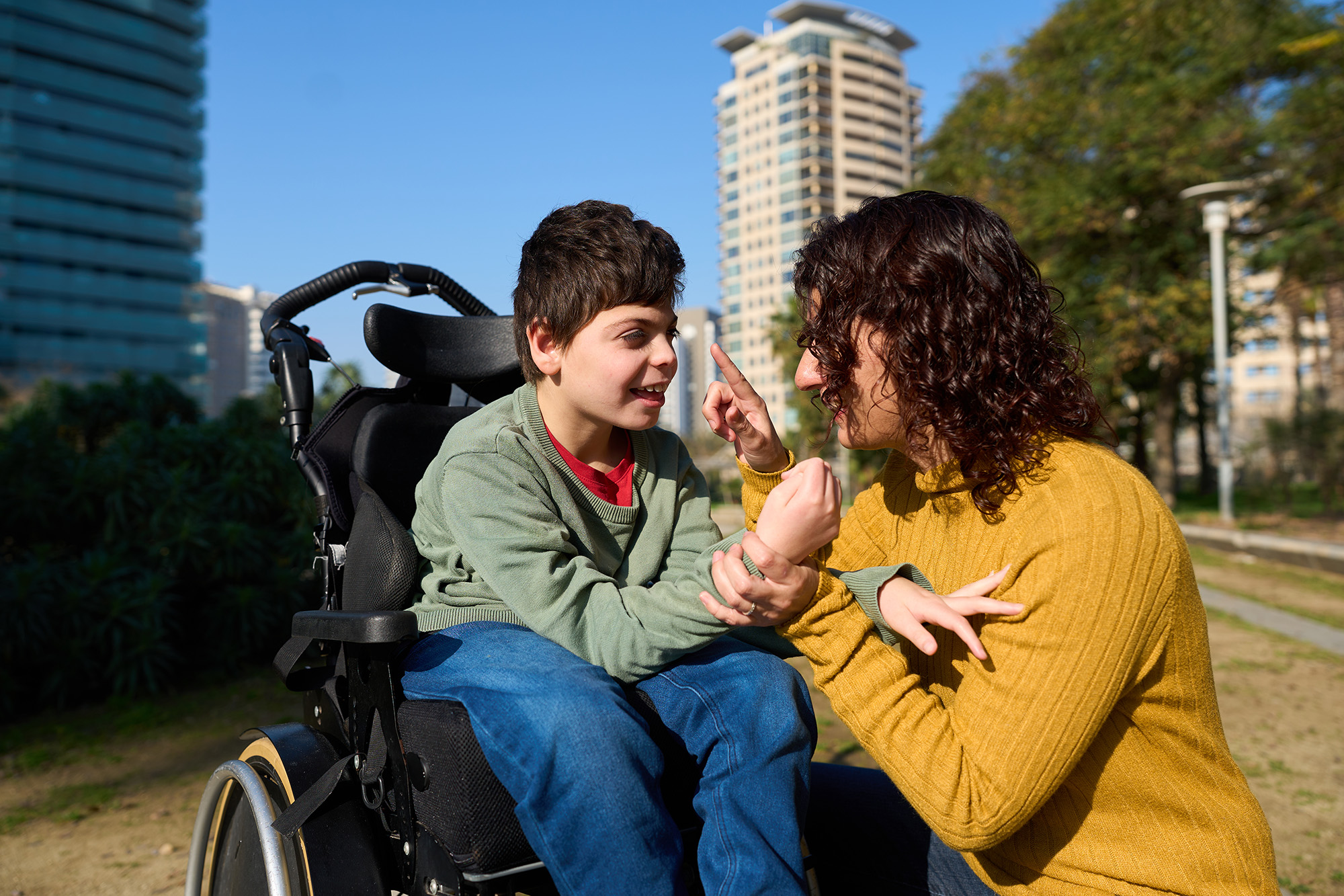 Bambino disabile sulla sedia a rotelle all'aperto insieme ai genitori